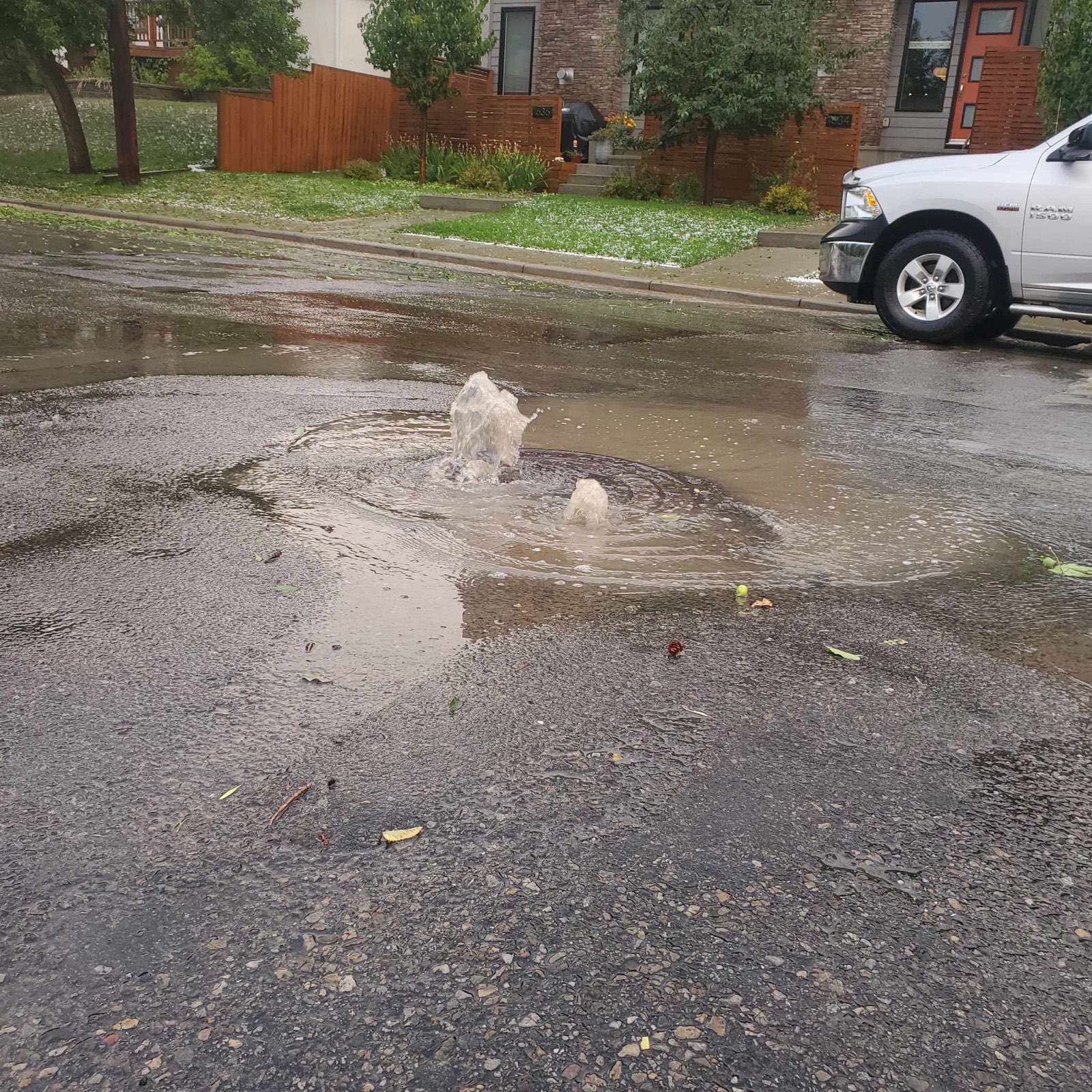 Water erupting from a sewer in a Calgary street with the Drain Wizards truck