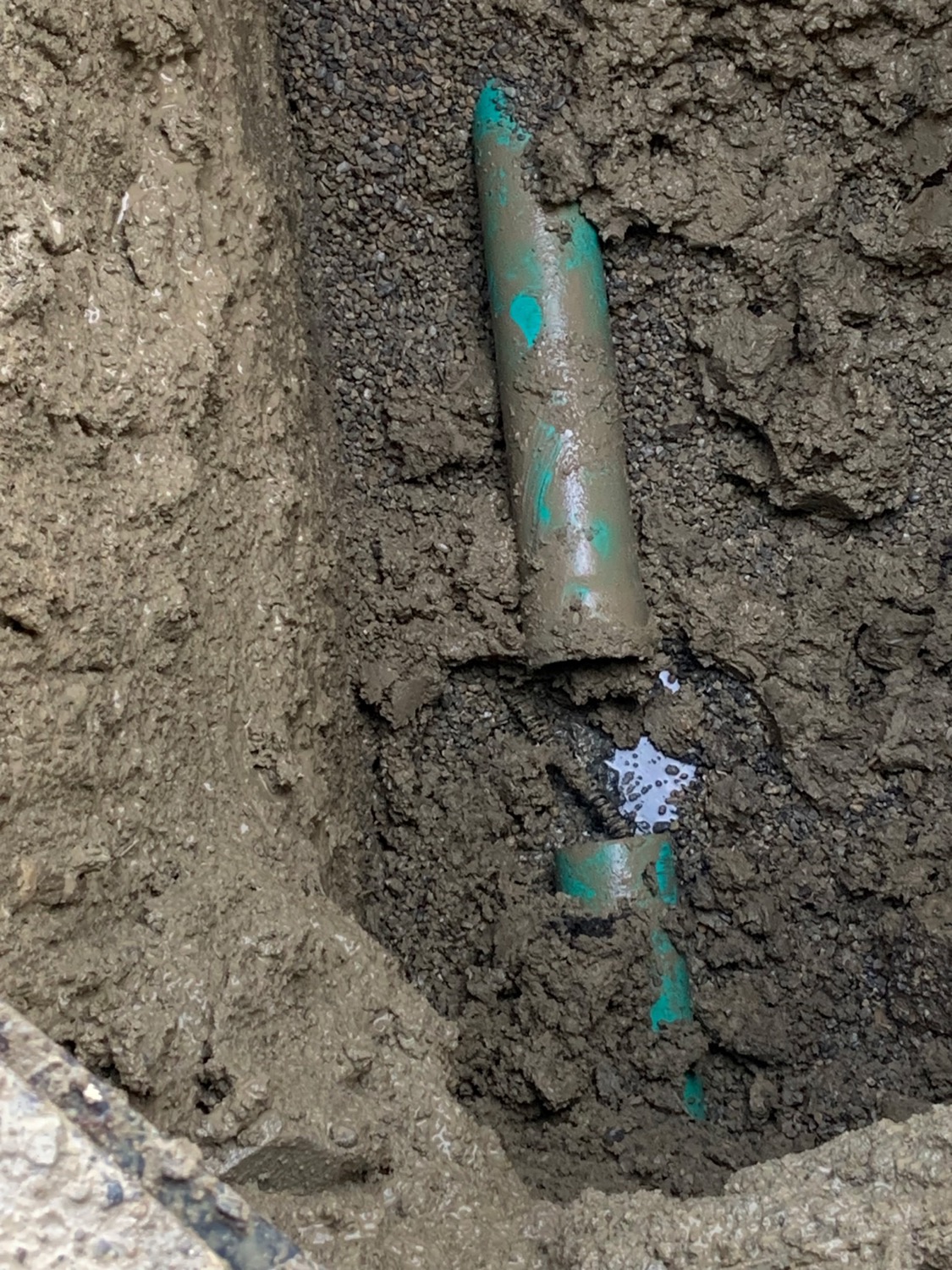 A cracked buried sewer pipe exposed in an excavation